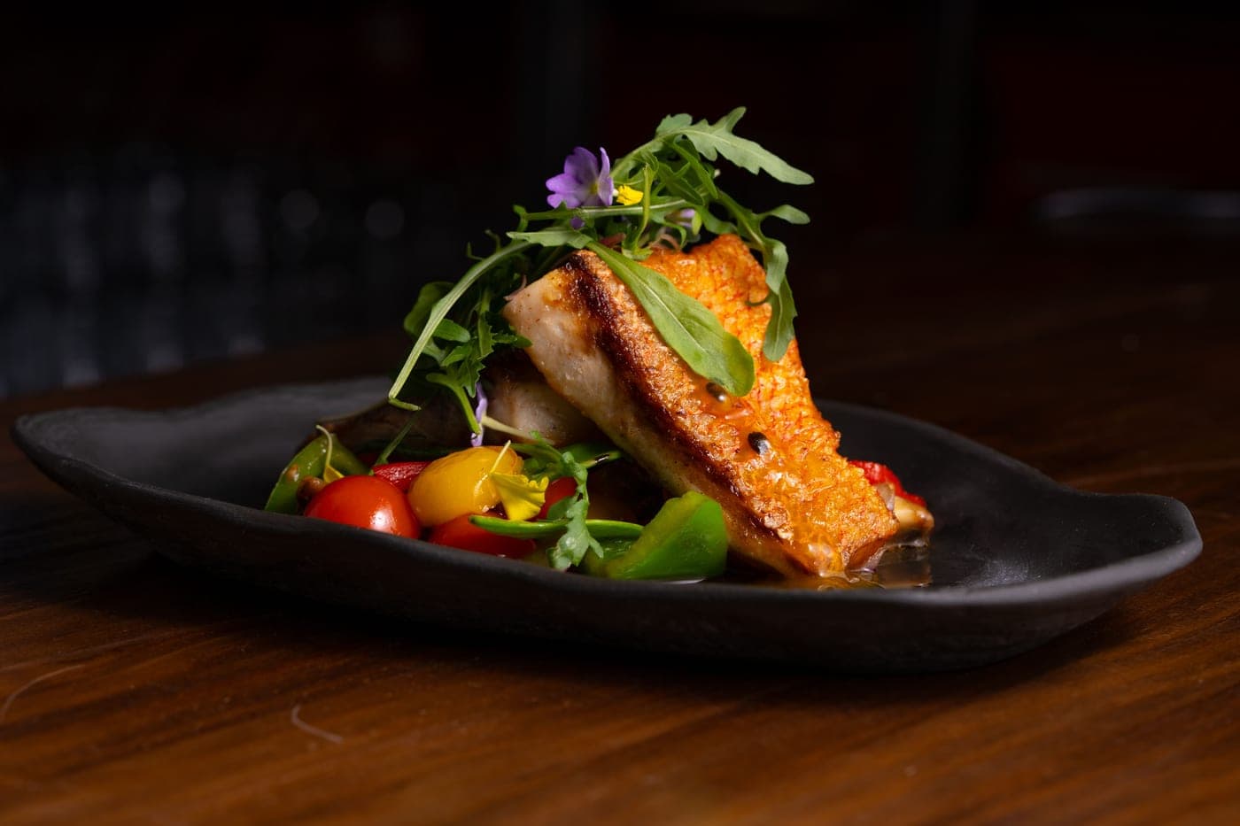 Dos de cabillaud et légumes sur une assiette sombre
